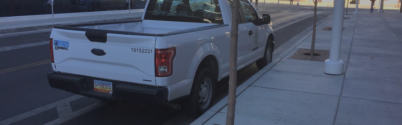 Albuquerque city planning department pickup, parked in a bike lane next to a "no parking bike lane" sign